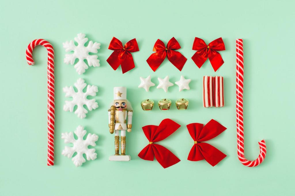 Diverse juldekorationer inklusive röda rosetter, godisrör, vita snöflingor, guldklockor, stjärnformade prydnadsföremål, en liten inslagen present och en vit nötknäppare, allt snyggt arrangerat på en mintgrön bakgrund.